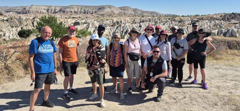      Group of people standing with the Cappadocia landscape in the background.
  