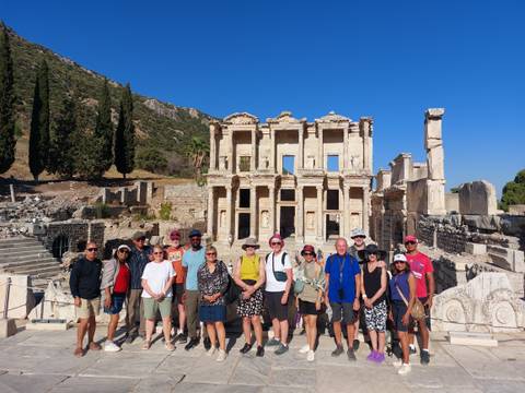       Tourists posing in front of ancient ruins on a sunny day.
  