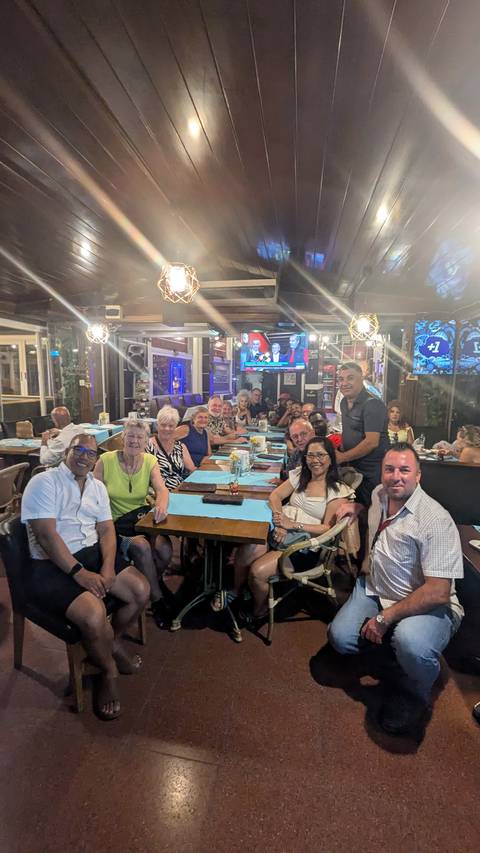       Group of people dining inside a restaurant with a TV screen.
  