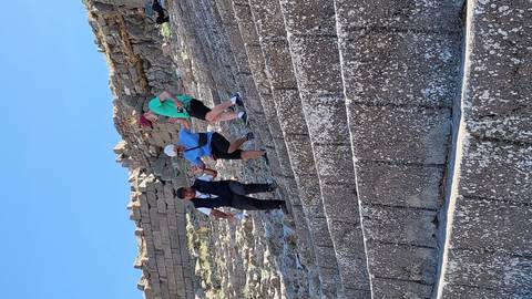       People walking down ancient stone steps of a theatre.
  