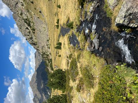       Flowing stream in a green mountain landscape.
  