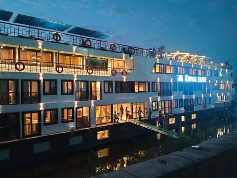      A luxury cruise ship docked at night with lights reflecting on water.
  