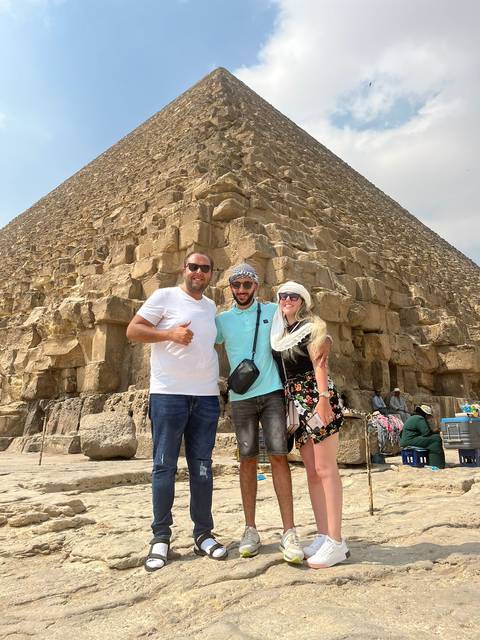       Group of tourists posing in front of the Great Pyramid.
  