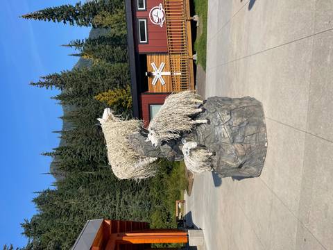 Sculpture of goats with a mountainous backdrop outside a visitor center.