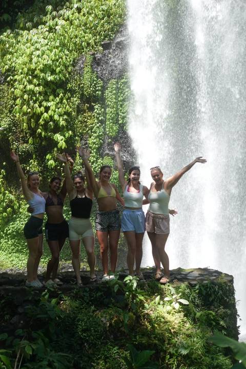 Group of friends posing with a waterfall backdrop.