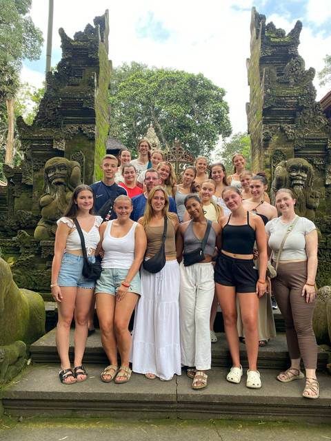       Large group posing in front of a carved stone entrance.
  