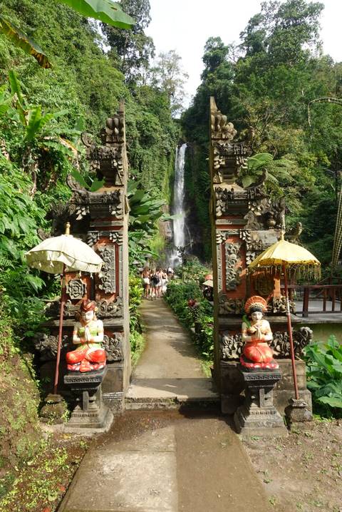 Pathway leading to a waterfall with traditional Balinese gate.