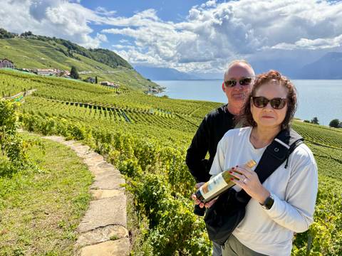 Couple standing in vineyard overlooking Lake Geneva.