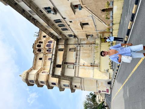       Person posing in front of a palace in India.
  