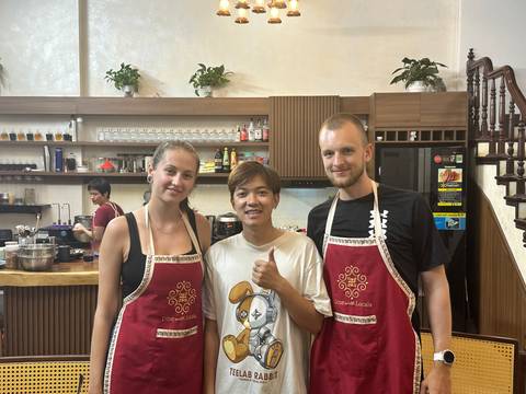 Three people in a kitchen setting, two wearing aprons.