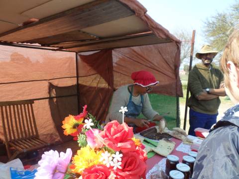 People preparing food at an outdoor market stall.