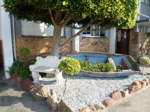 Rowboat converted into a planter in front of a building.