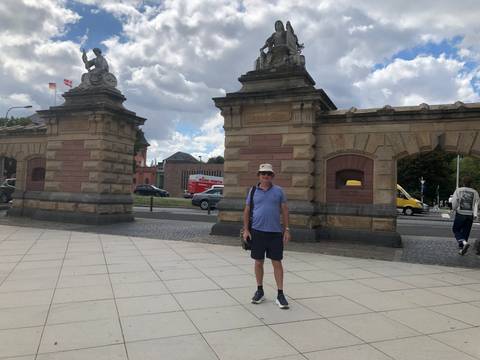 Tourist standing in front of large gates in a city.