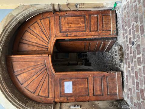 Large wooden door slightly ajar with cobblestone path.