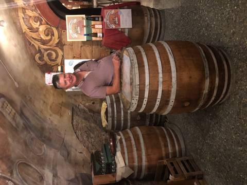       Man standing inside a wine cellar with barrels.
  