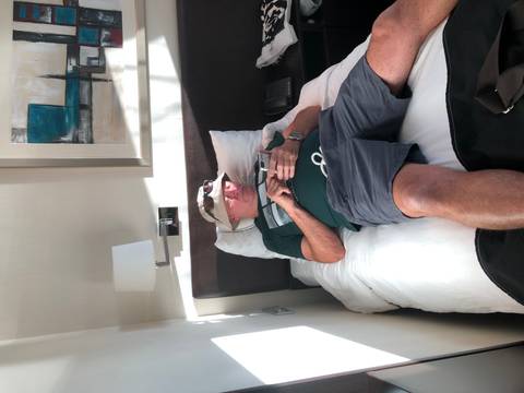 Man resting on a hotel bed using a phone.