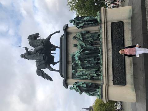       Woman posing in front of a statue of a rider on horseback.
  