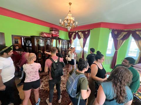       A group of people inside a room with bright green walls.
  