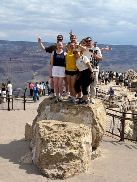 People posing at the Grand Canyon with a view of the canyon.