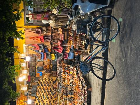       Shop display with colorful leather bags, shoes, and a bicycle parked outside.
  