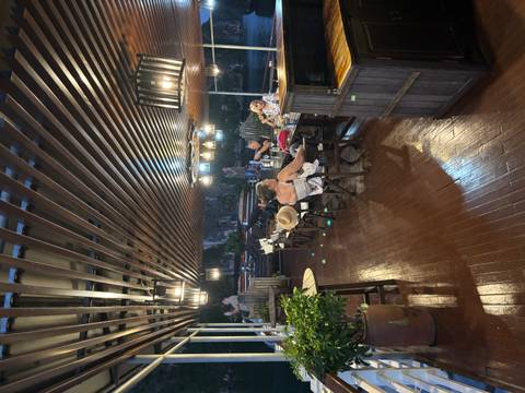       People dining and relaxing on a wooden deck of a boat during dusk.
  