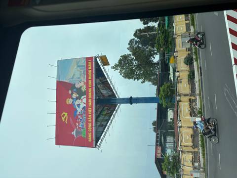       Billboard with Vietnamese text and graphic on a city street.
  