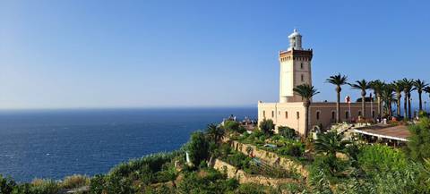       Lighthouse surrounded by greenery overlooking the sea
  