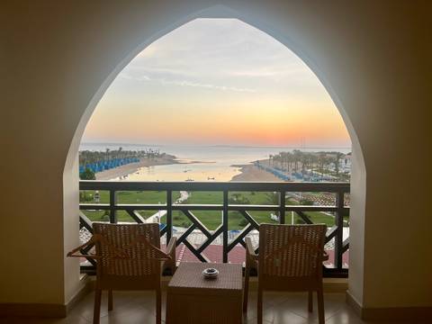 View of a balcony overlooking a beach at sunset.