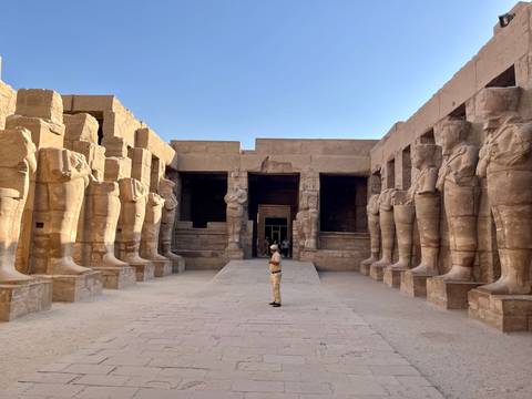 Person standing in an ancient courtyard with monumental statues.