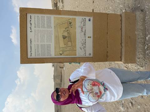 Person standing next to a sign at the Step Pyramid Complex.