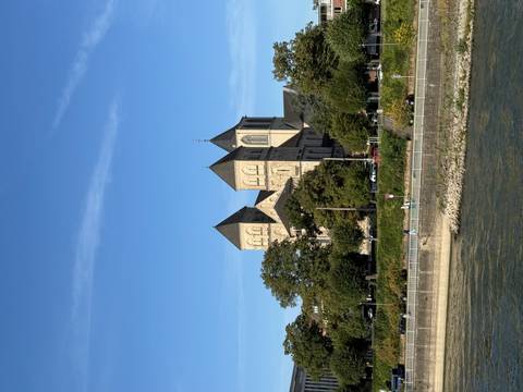 Historic building with twin towers near a river.