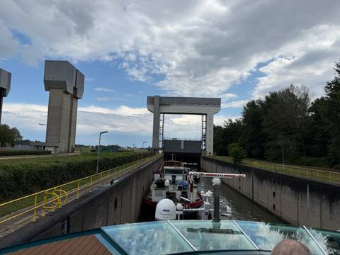 Lock system with boats on a river under a cloudy sky.