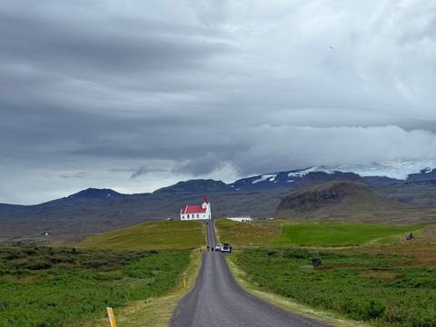       Scenic view of a church on a hill with mountains in the background.
  