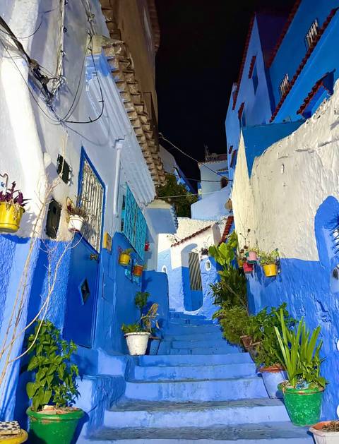 Blue-colored narrow street with traditional Moroccan architecture at night.