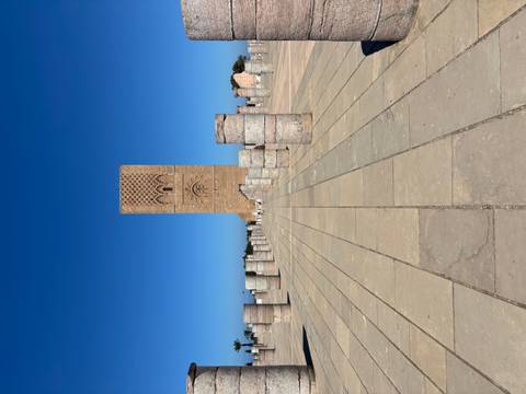 Paved area with Roman ruins and a tall tower in the background.