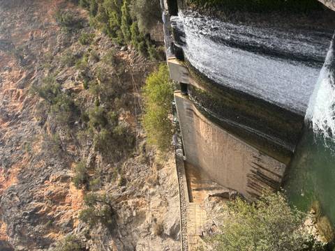 Waterfall cascading over a dam with a rocky mountain behind.