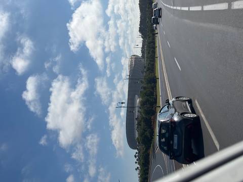 Modern stadium near a road with a parked car and clear skies.