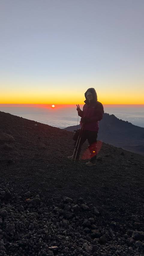 Hiker enjoying sunrise on a mountain trail.