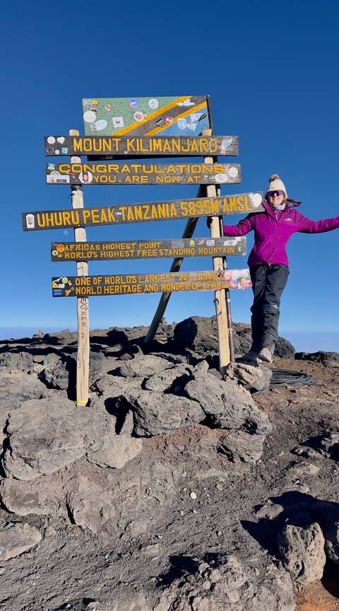 Hiker at Uhuru Peak summit sign.