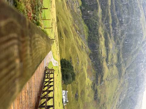 Mountain landscape with wooden bridge in foreground.
