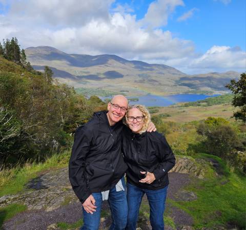 Smiling couple in front of a scenic lake.