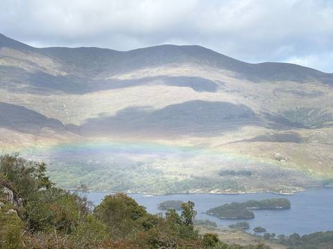 A scenic view of a mountain landscape with a visible rainbow.