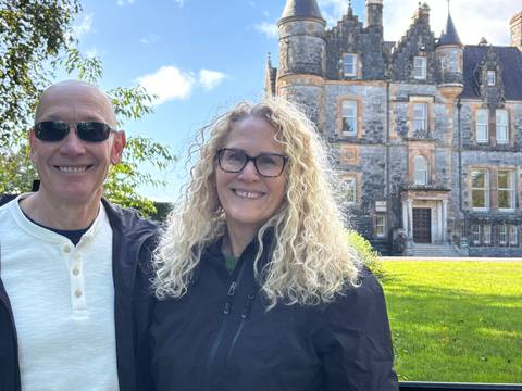 A couple smiling in front of a historical building.