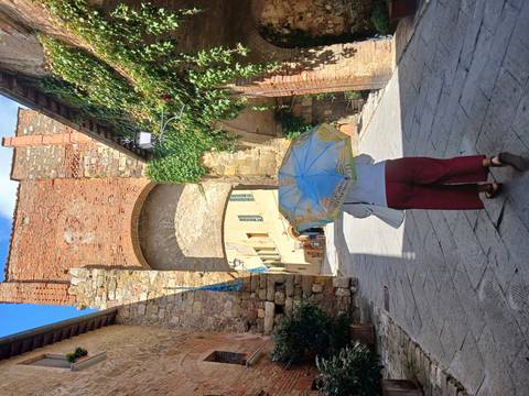       A person walking through a historic archway in a charming old town street.
  