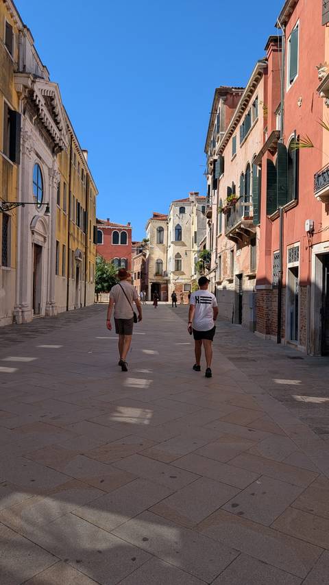Two people walking down a picturesque alley in a European city.