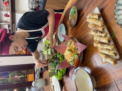 Chef preparing Vietnamese spring rolls on a table with various dishes.