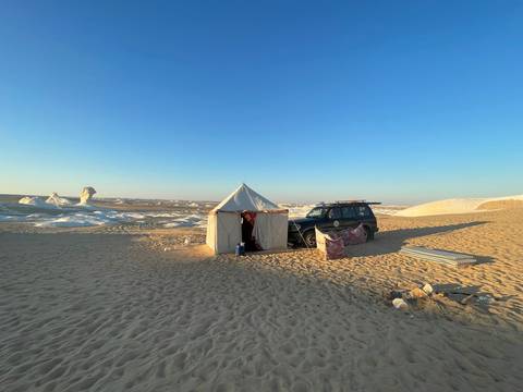       Tent and a car in a desert setting.
  