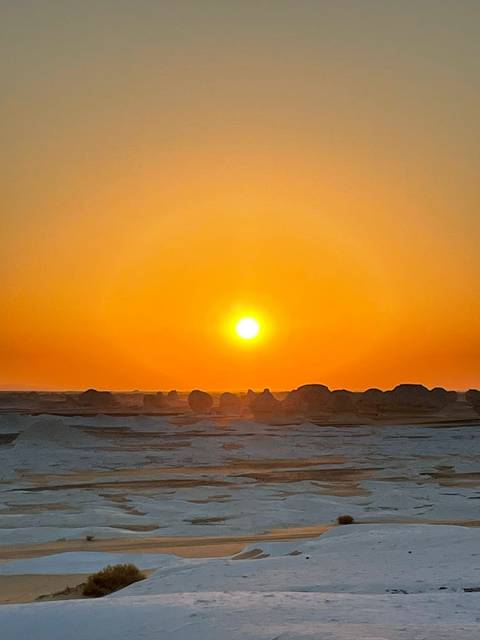Sunset over the desert with rock formations.