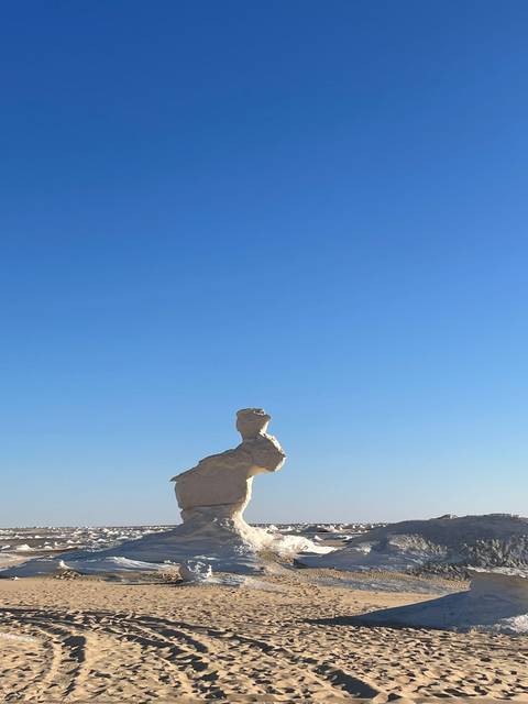 Lone rock formation against a clear blue sky.