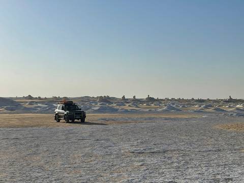 An SUV on a vast desert landscape.